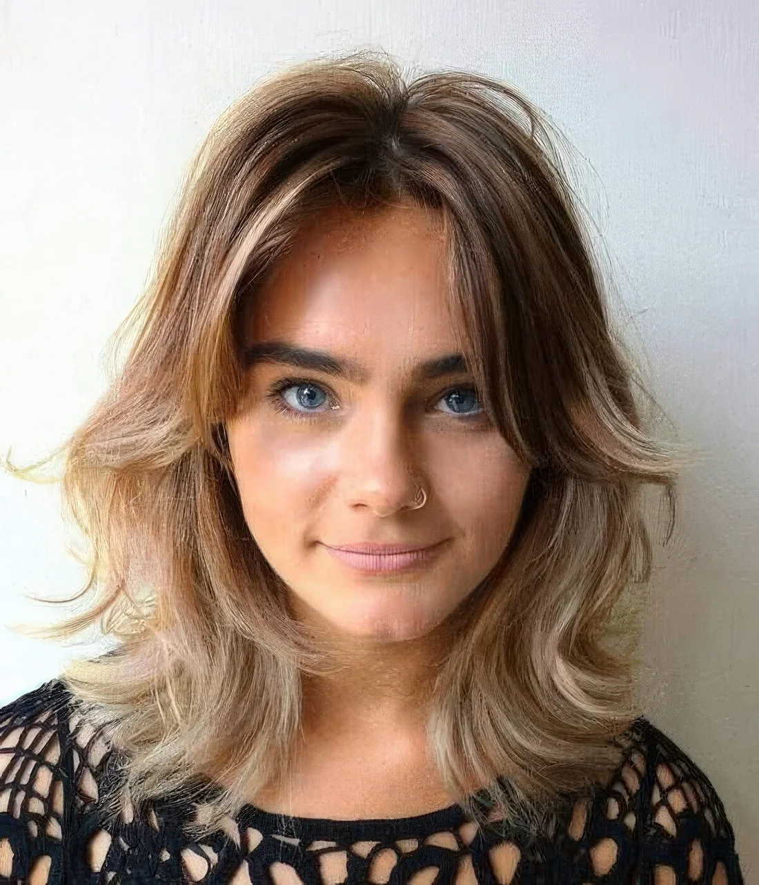 Light burnette shaggy bob with blonde balayage, center part, side bangs and waves.