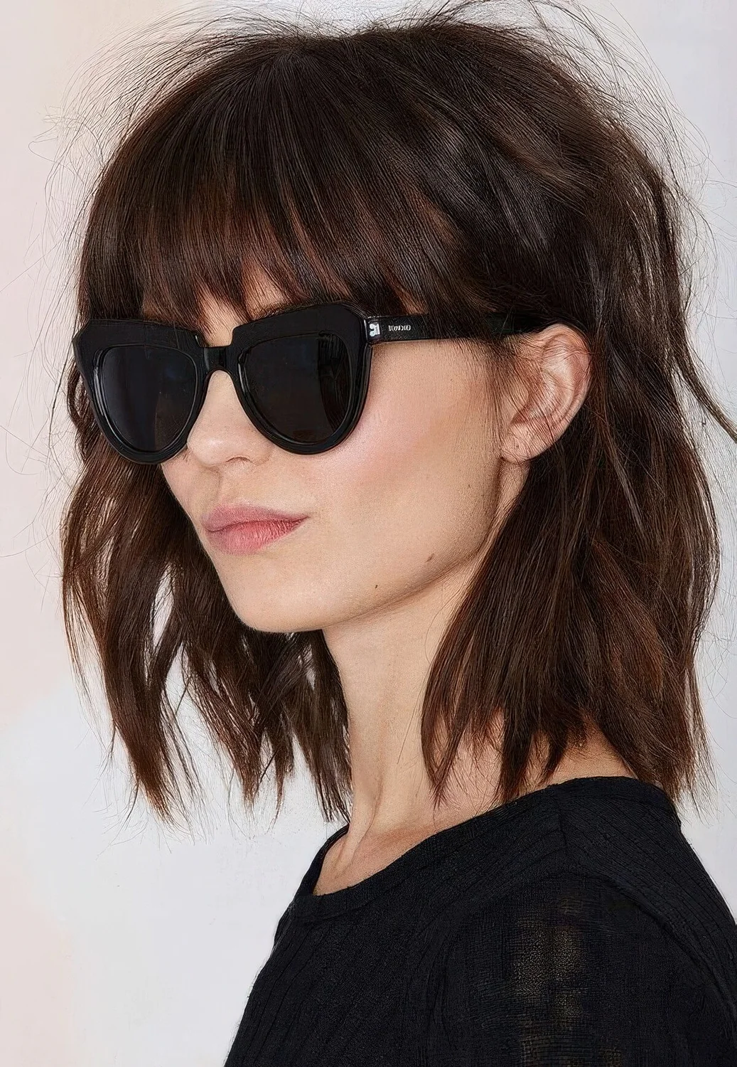 Shaggy brown shoulder-length bob with classic bangs and messy waves.