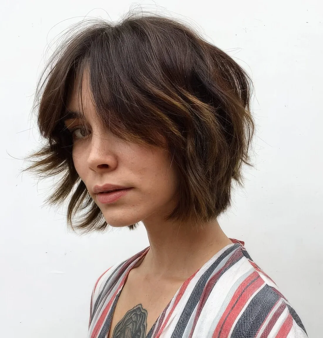 Textured brown chin-length bob with a bit of caramel balayage and a lot of texture.