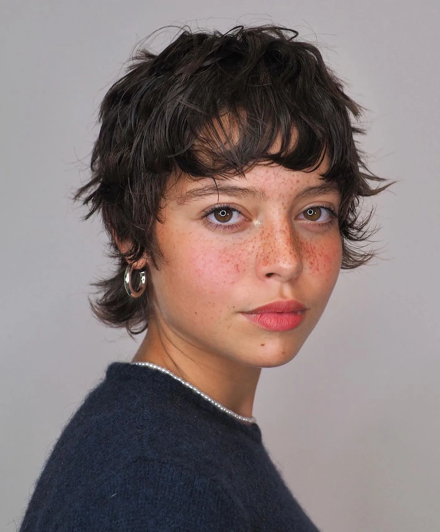 ear wavy brunette pixie with micro fringe shown as a shaggy pix mullet idea