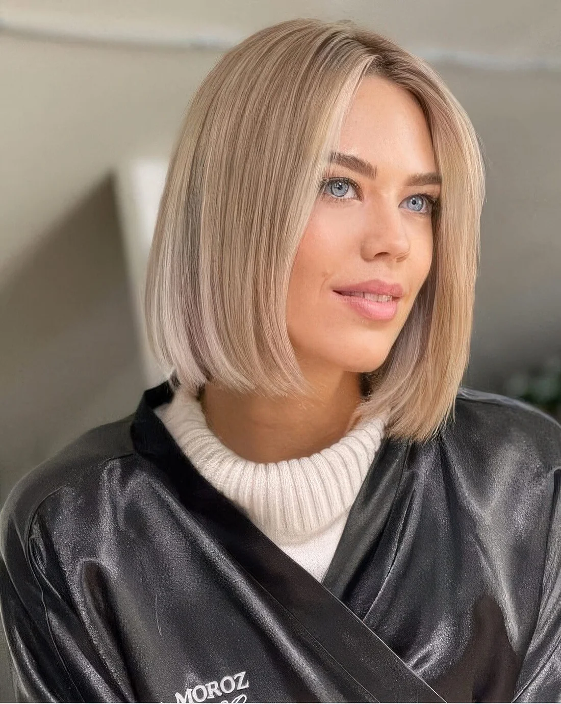 Blonde blunt midi bob with a soft blonde shade and middle part.