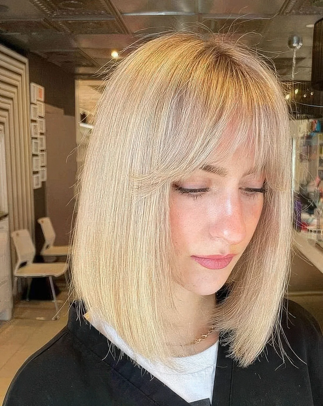 Photo showing blonde long bob with wispy bangs, with the hairstyle clearly visible.