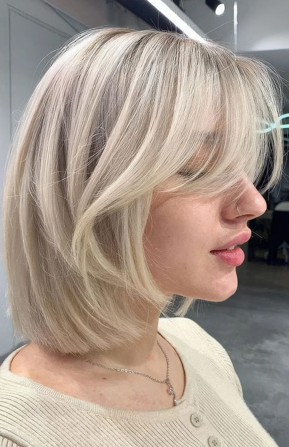 Chic icy blonde long bob with curtain bangs.