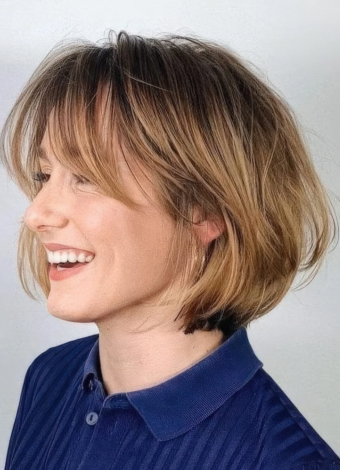 Chin-length bob with honey blonde balayage and long curtain bangs, curved ends and a bit of volume.