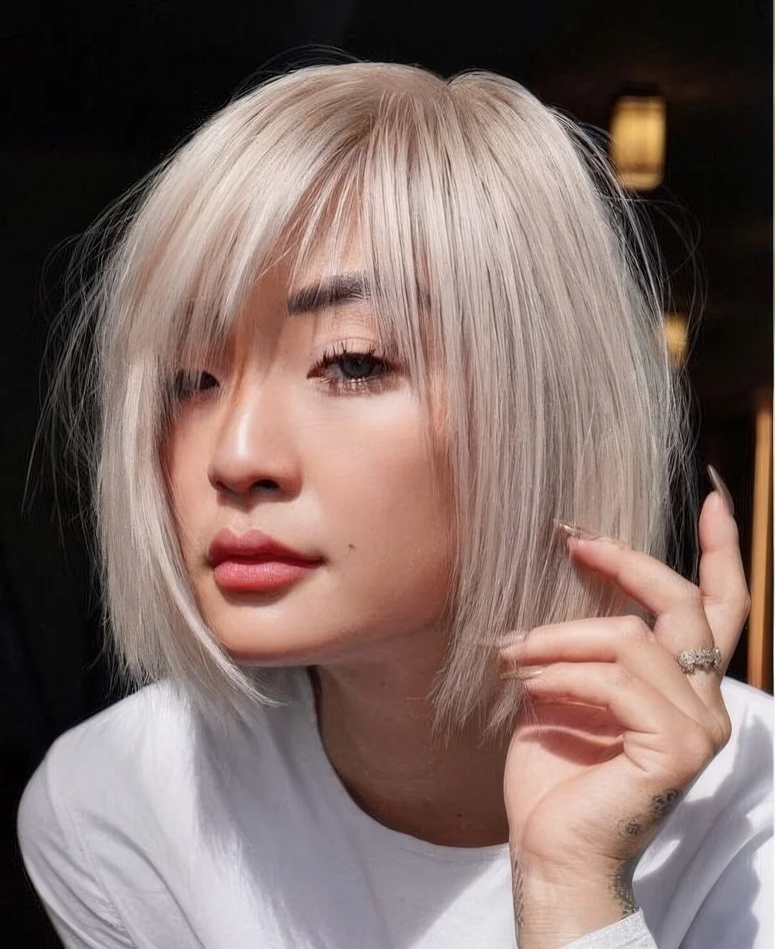 Chin-length platinum blonde bob with wispy bangs and side part.