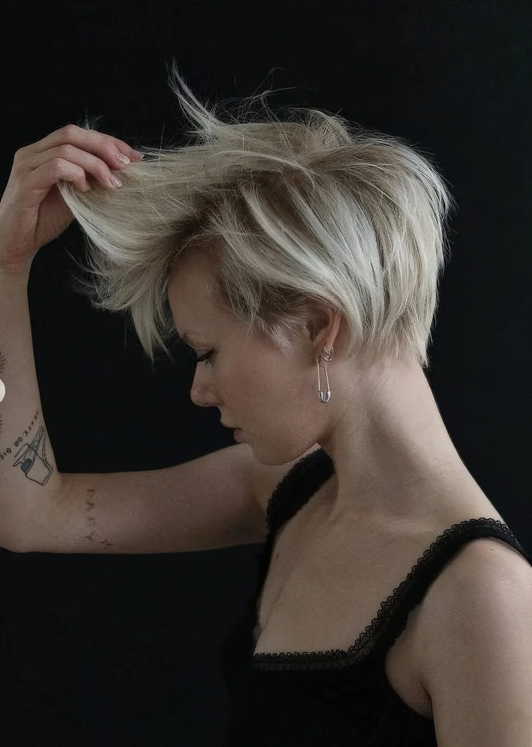 Long pixie with side part, straight textured hair and curled ends plus a lot of volume.