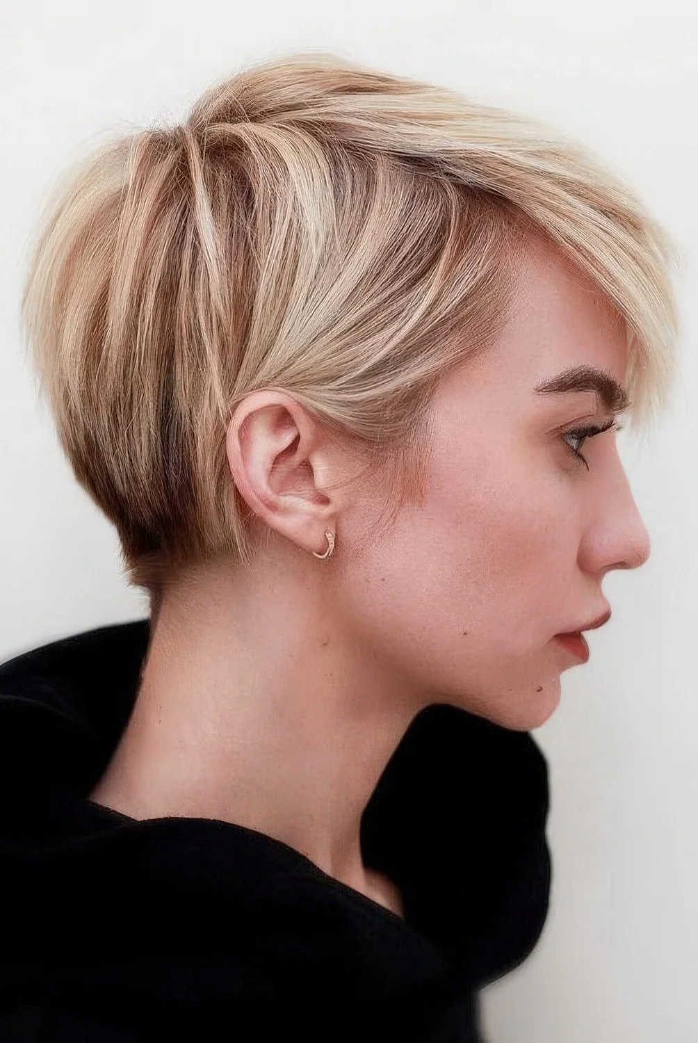 Long pixie with warm blonde balayage and textured hair plus a lot of volume.