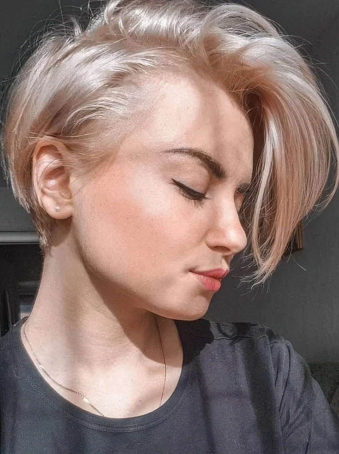Long side pixie haircut in a platinum blonde shade.