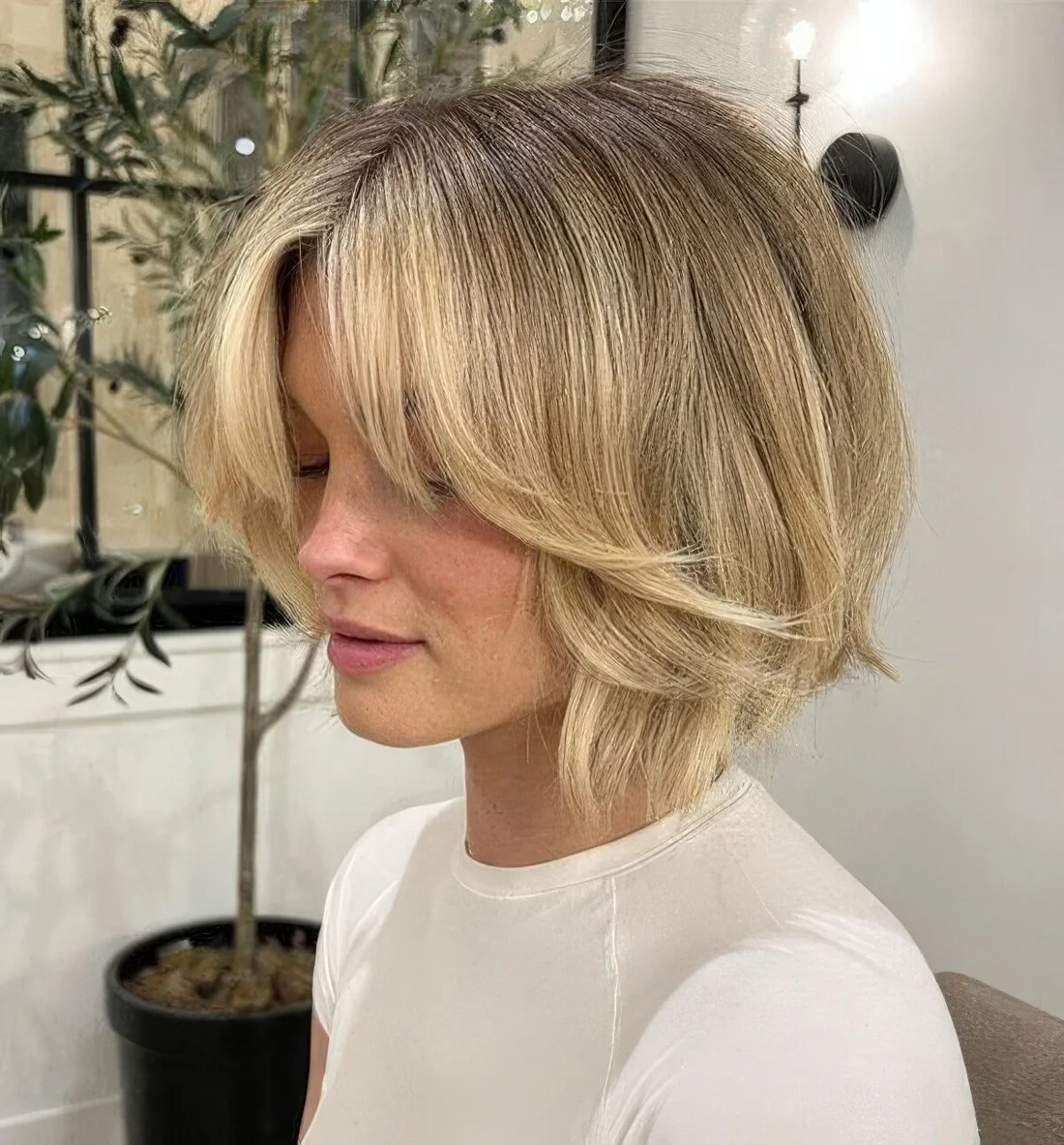 Chin-length golden layered bob with curtain bangs and a lot of volume.