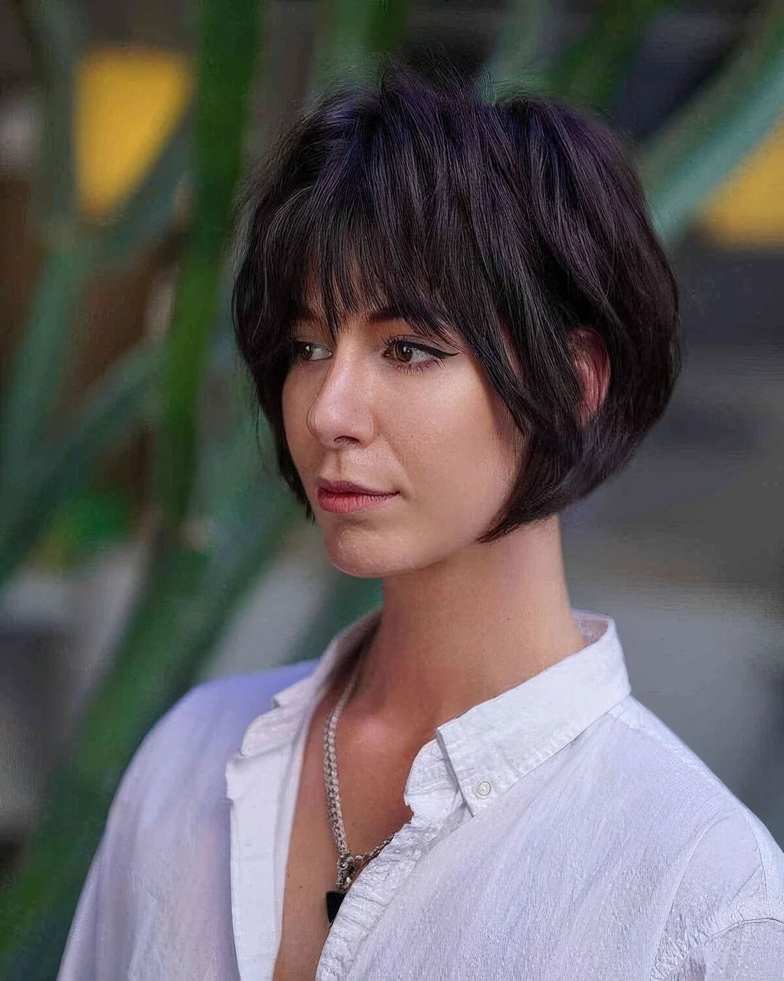 Black layered jaw-length bob with wispy bangs and shaggy layers.