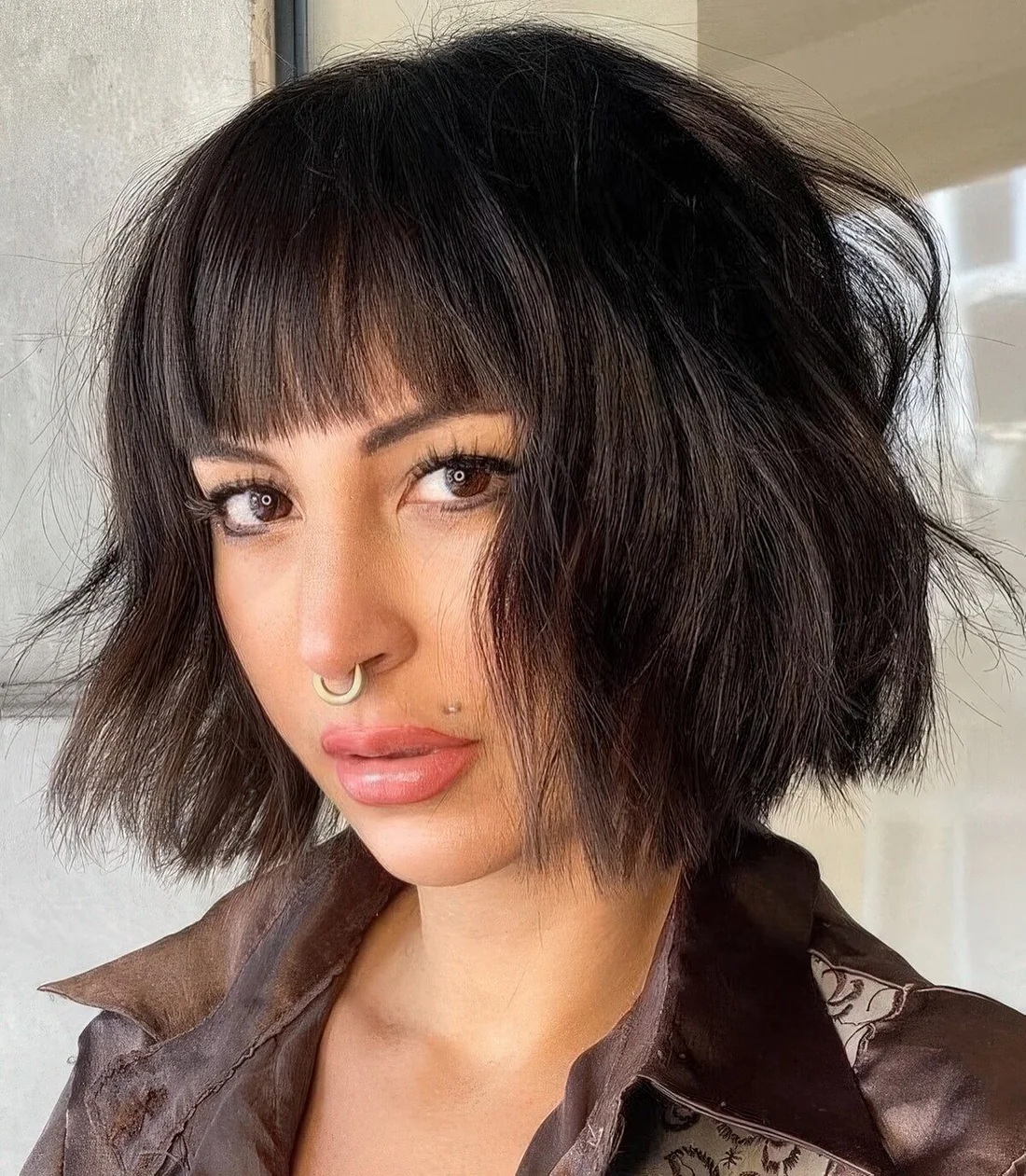 Black textural and wavy chin-length bob with waves and blunt bangs.