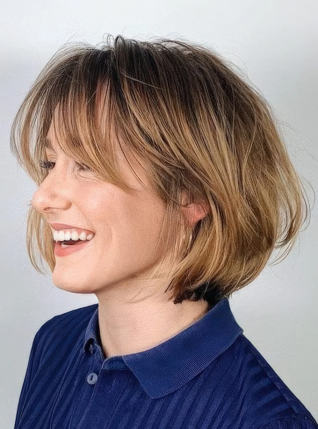 Chin-length bob with honey blonde balayage and long curtain bangs, curved ends and a bit of volume.