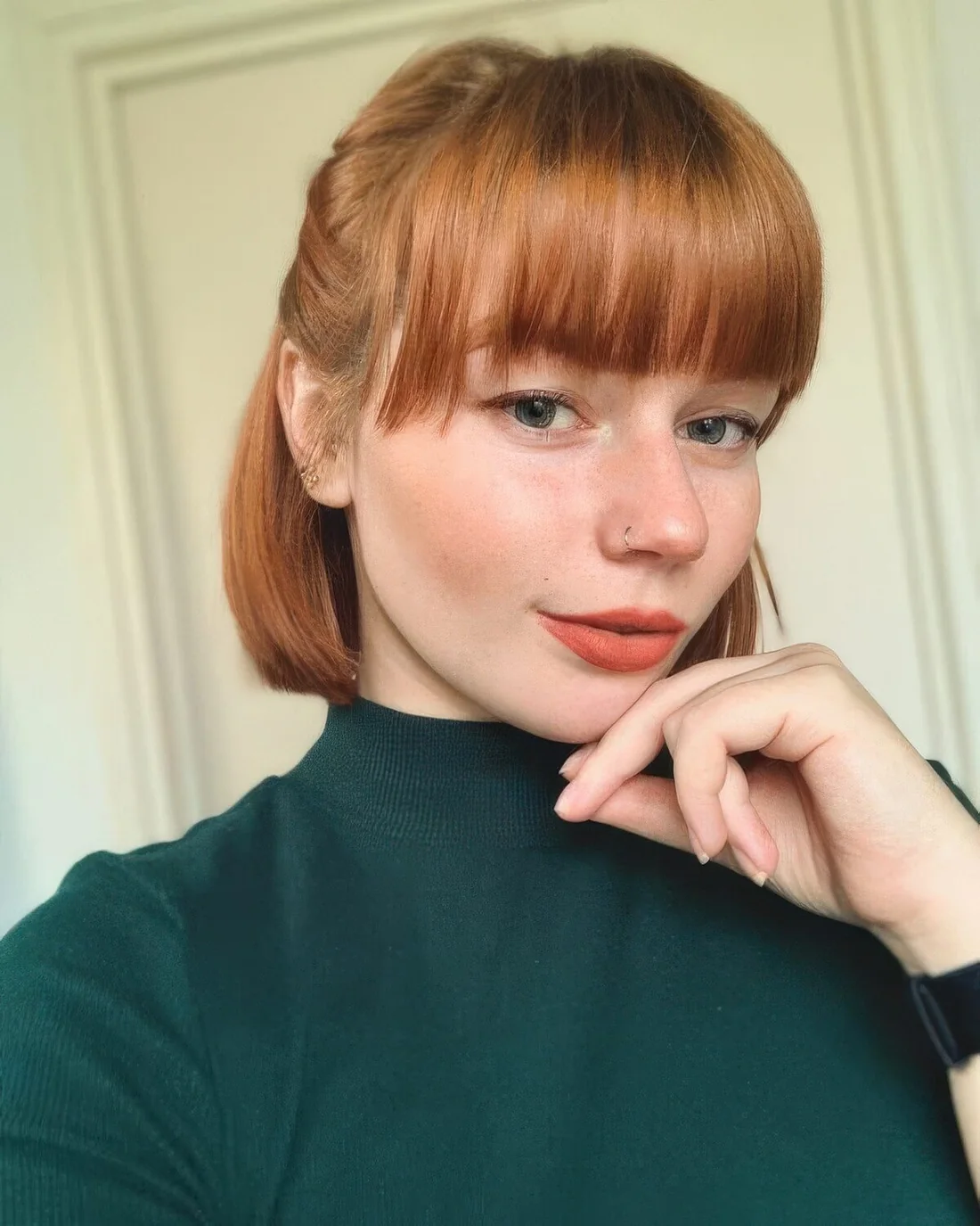 Chin-length ginger bob with a classic fringe styled as a half updo.