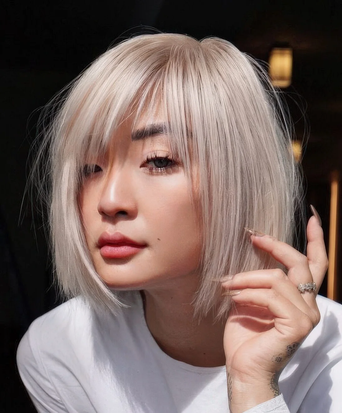 Chin-length platinum blonde bob with wispy bangs and side part.