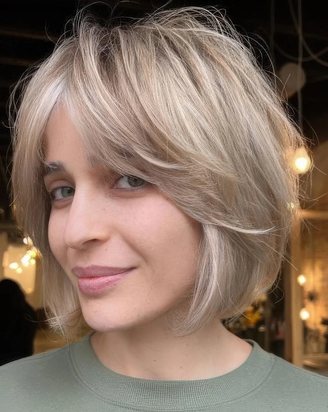 Cold blonde feathered chin-length bob with curtain bangs.