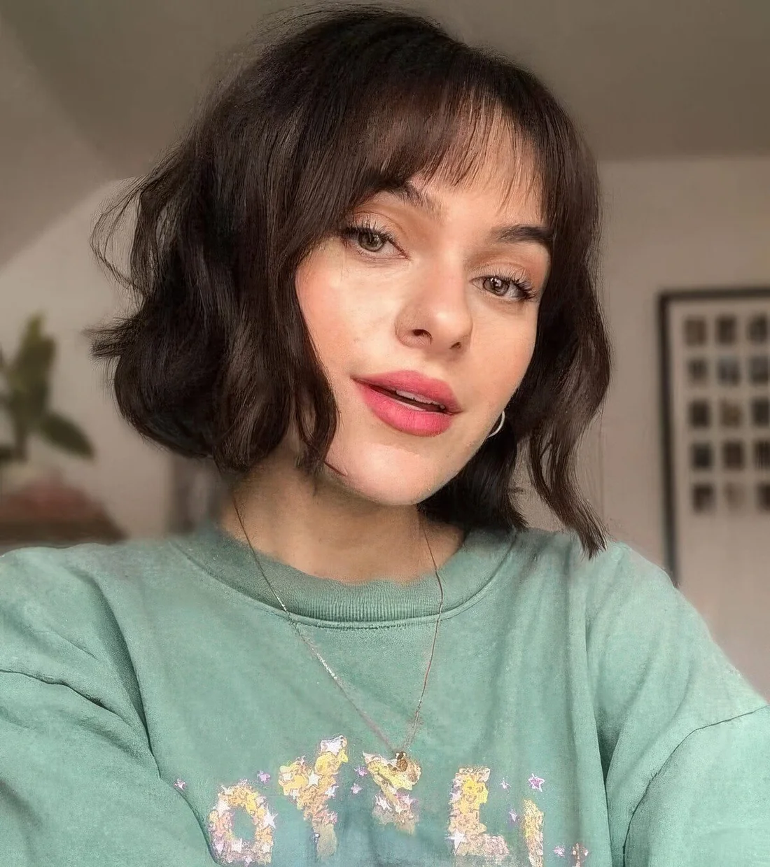 Dark brown chin-length wavy bob with wispy bangs.