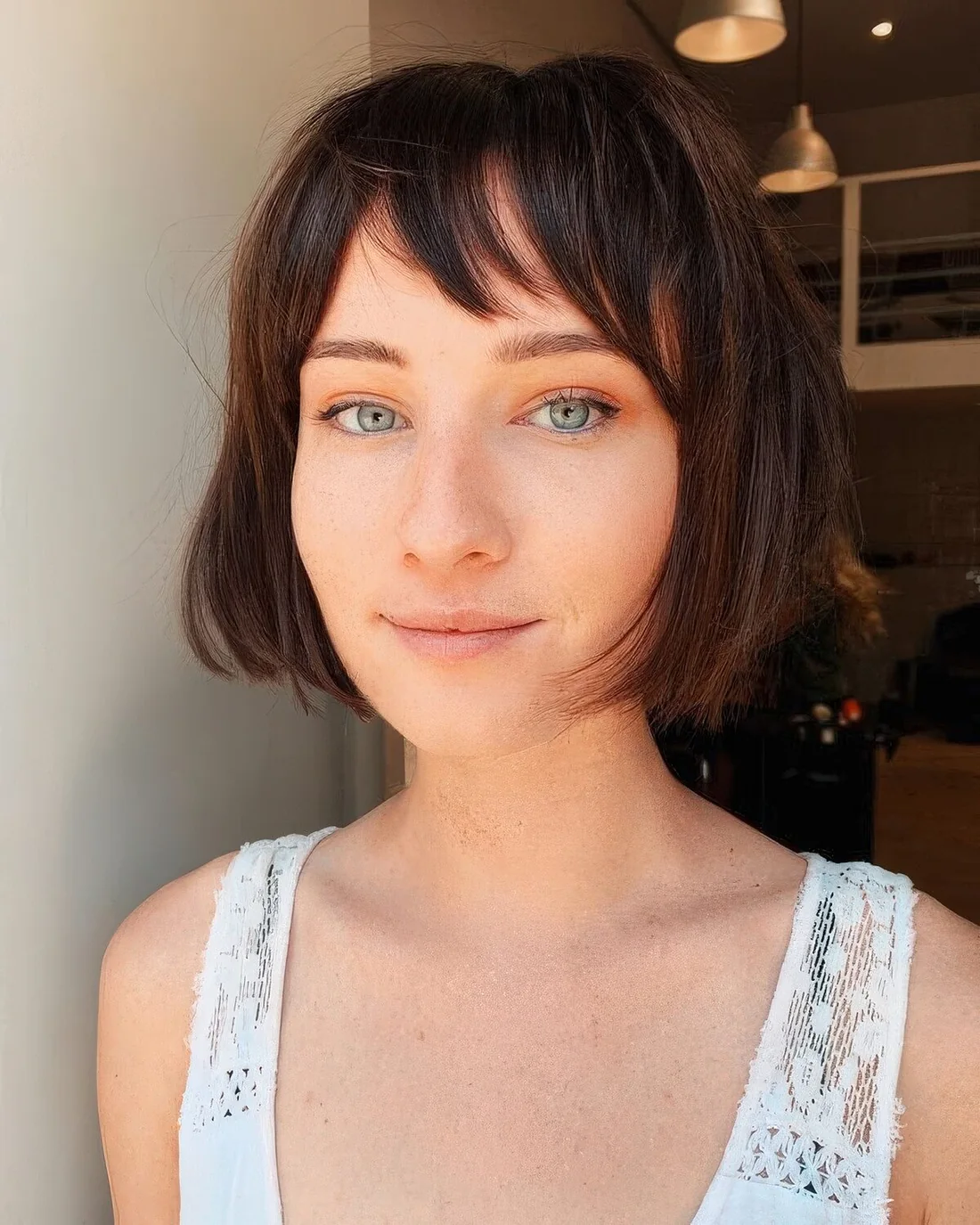 Dark brunette chin-length bob with wispy bangs.