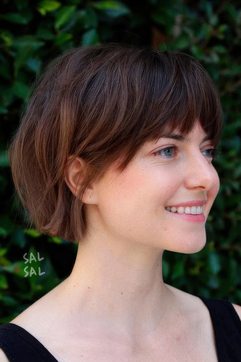 Dark brunette jaw-length bob with caramel balayage and layered bangs.