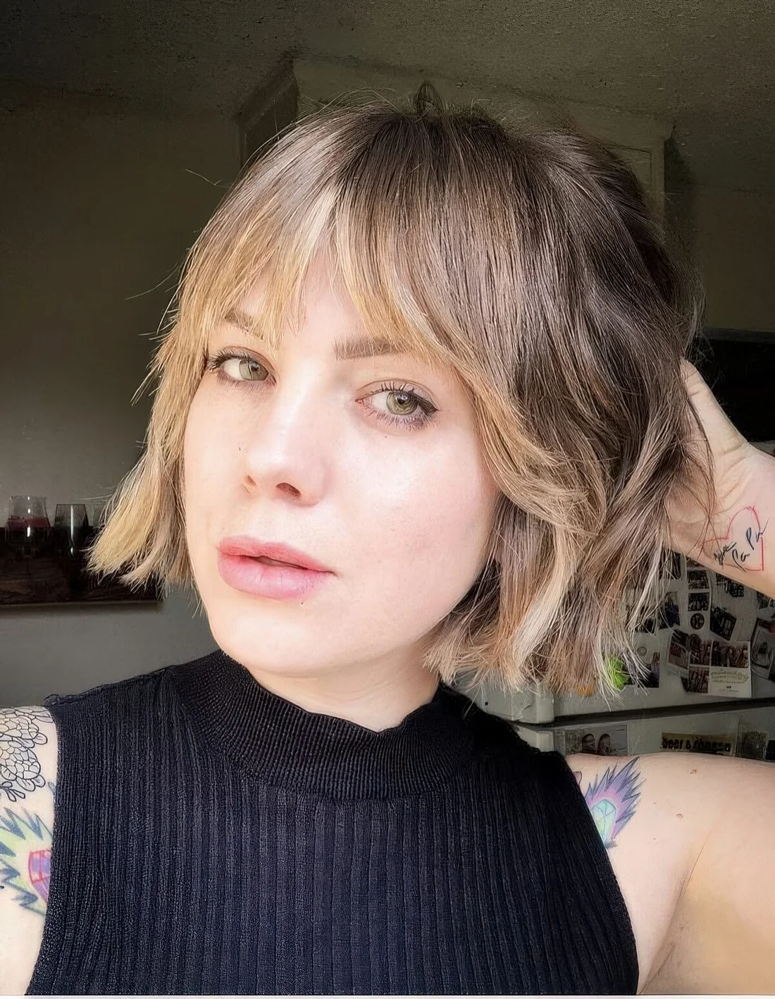 Jaw-length bob with blonde balayage and wispy bangs plus a bit of waves.