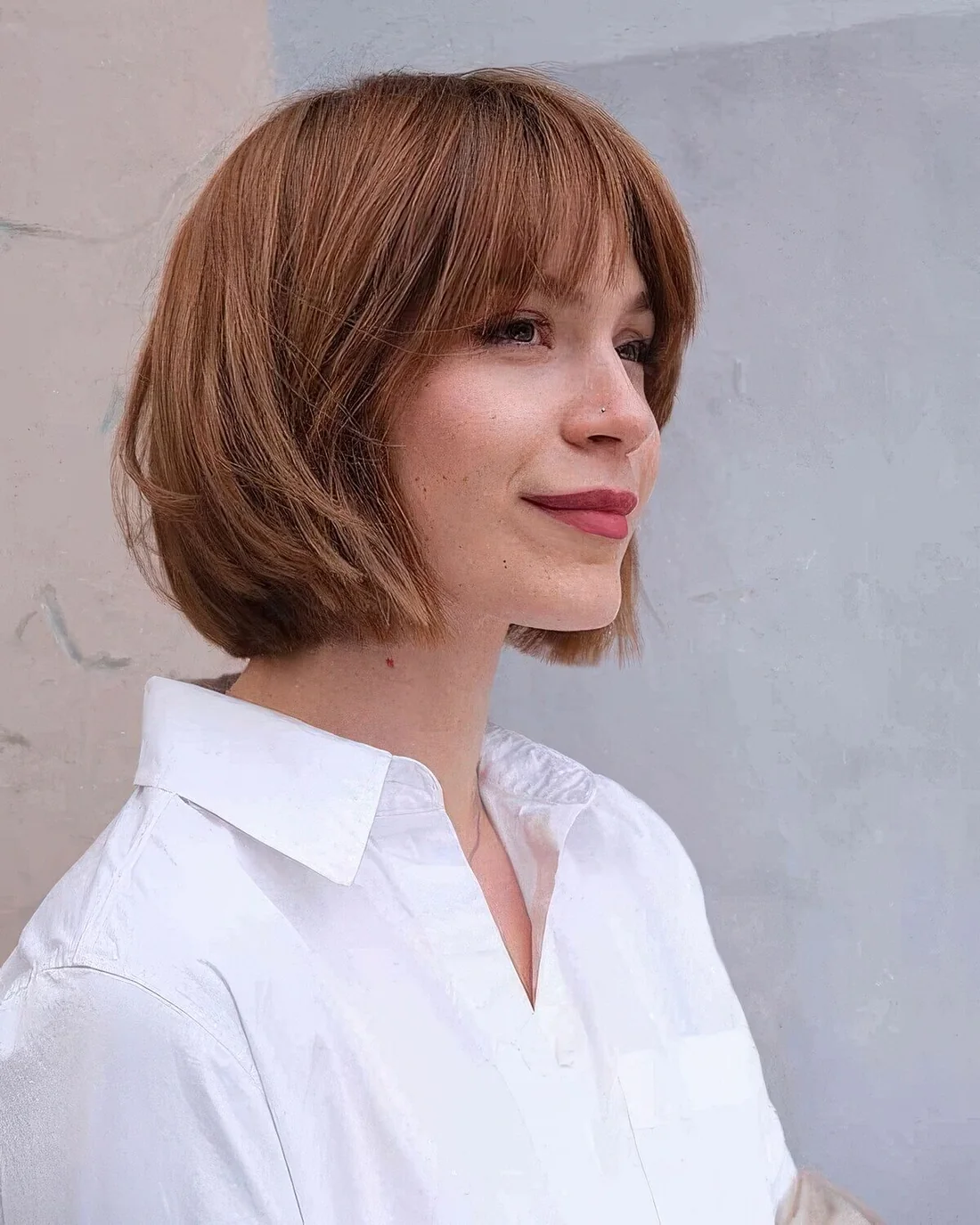 Ginger brunette choppy bob with wispy bangs and caramel balayage.