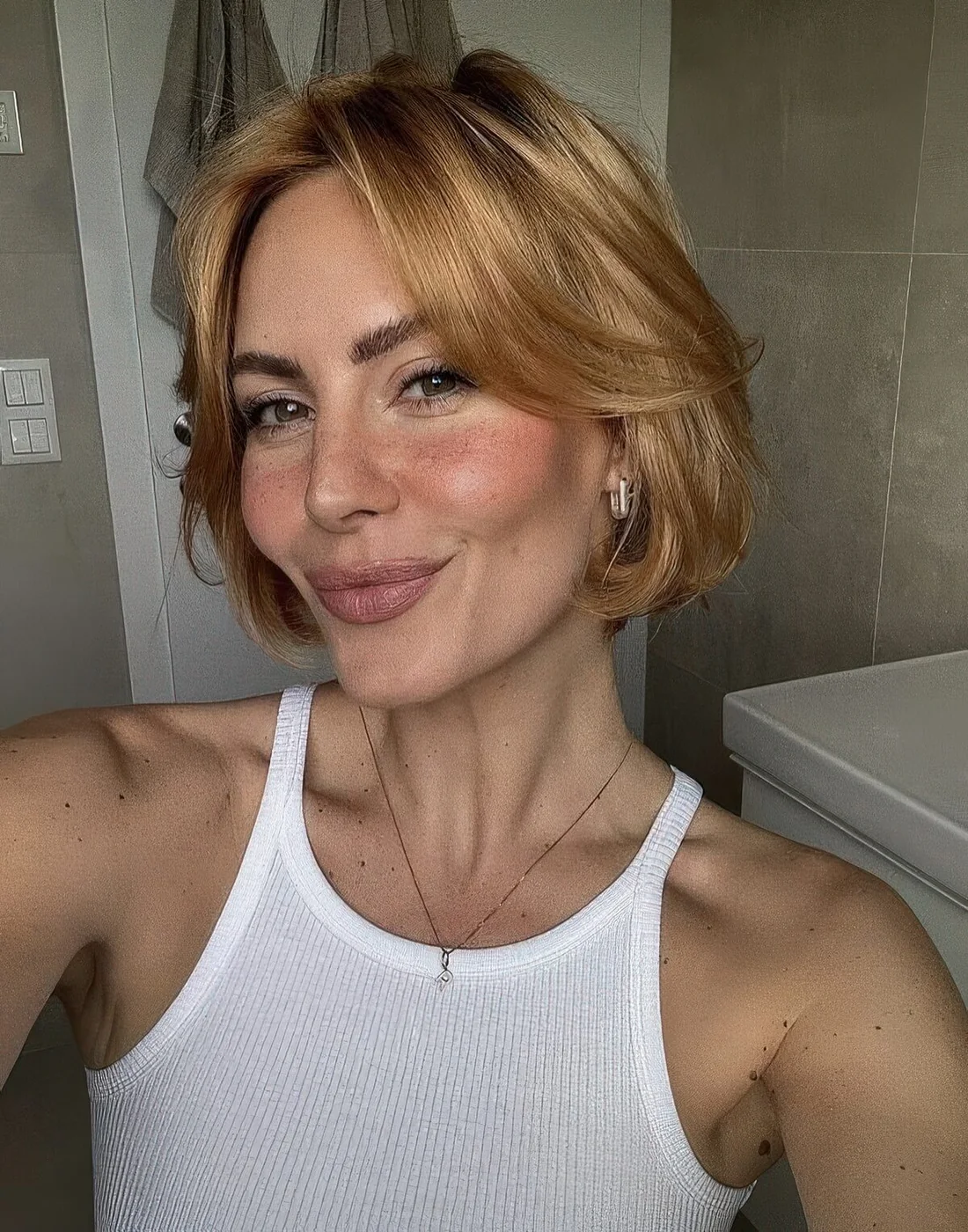 Honey blonde jaw-length bob with curtain bangs and a bit of waves.