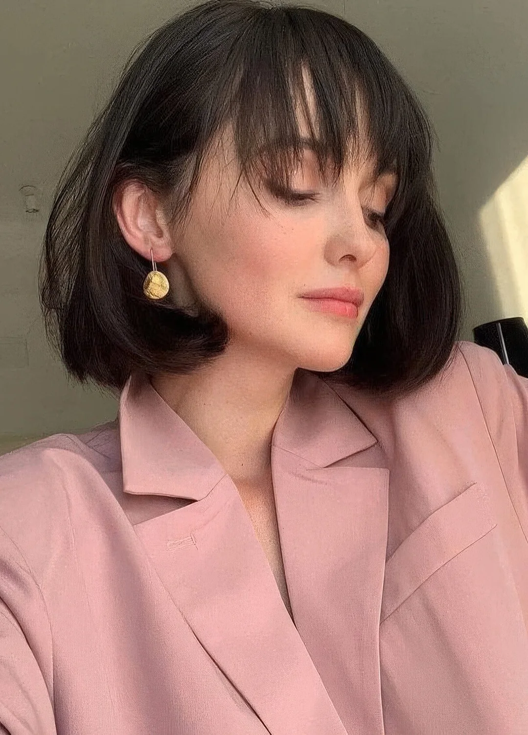 Medium black bob with rounded ends and wispy bangs that accent the eyes and the face.