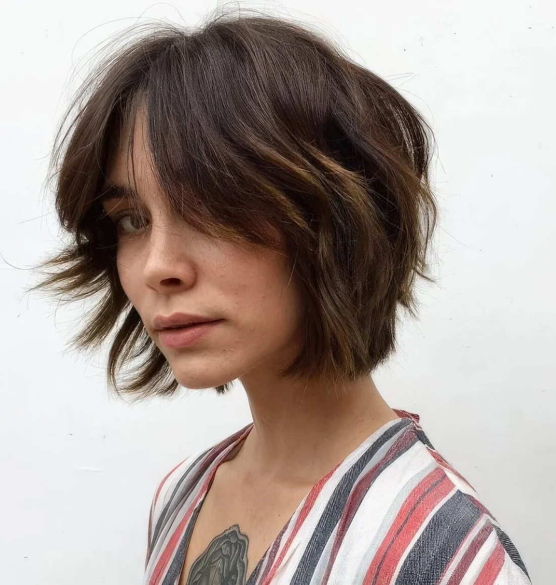 Textured brown chin-length bob with a bit of caramel balayage and a lot of texture.