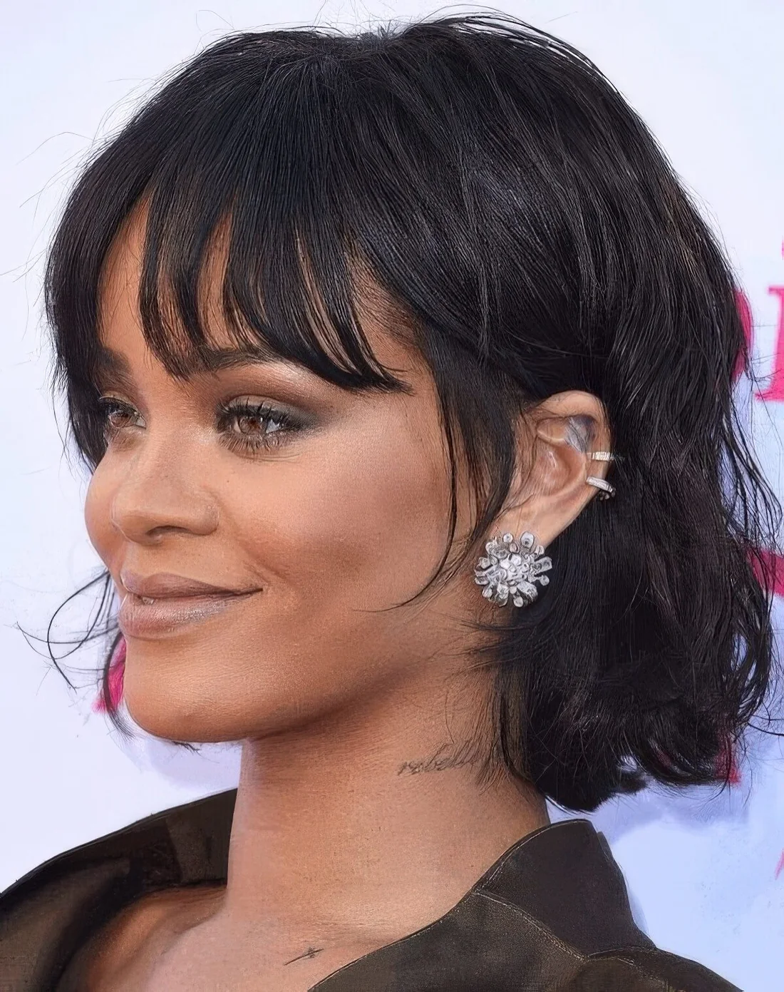 Rihanna rocking a black chin-length bob with messy waves and wispy bottleneck bangs.