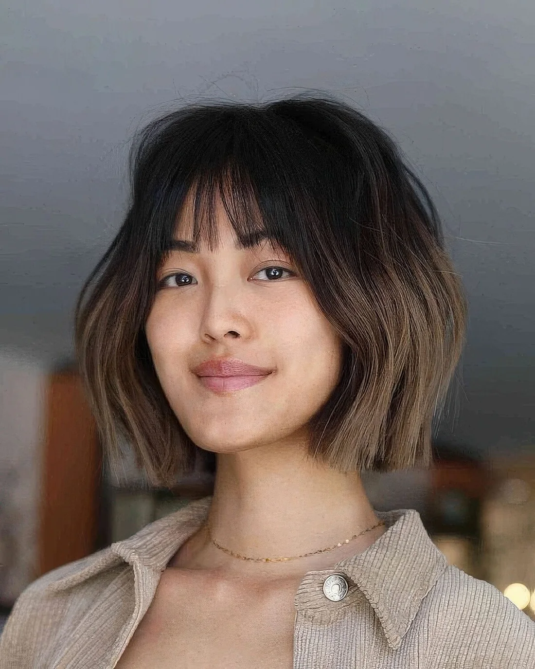 Chic chin-length layered bob with wispy bangs and an ombre effect.