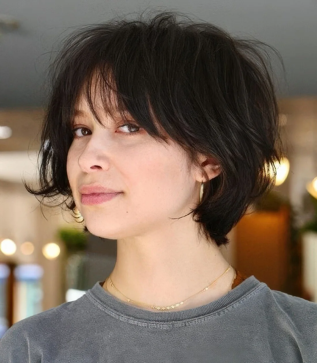 Dark brown feathered short bob with wispy bangs.