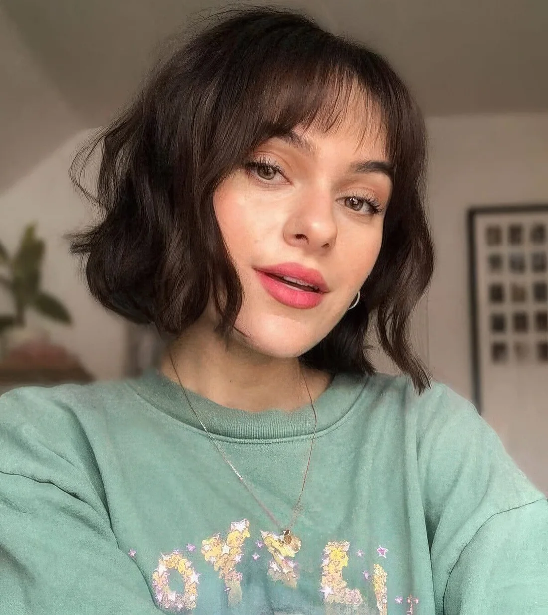 Dark brown chin-length wavy bob with wispy bangs.