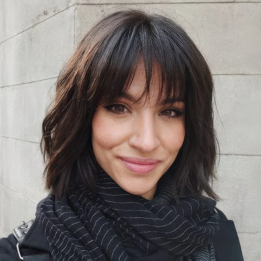 Dark brunette shaggy chin-length bob with outgrown wispy bangs.