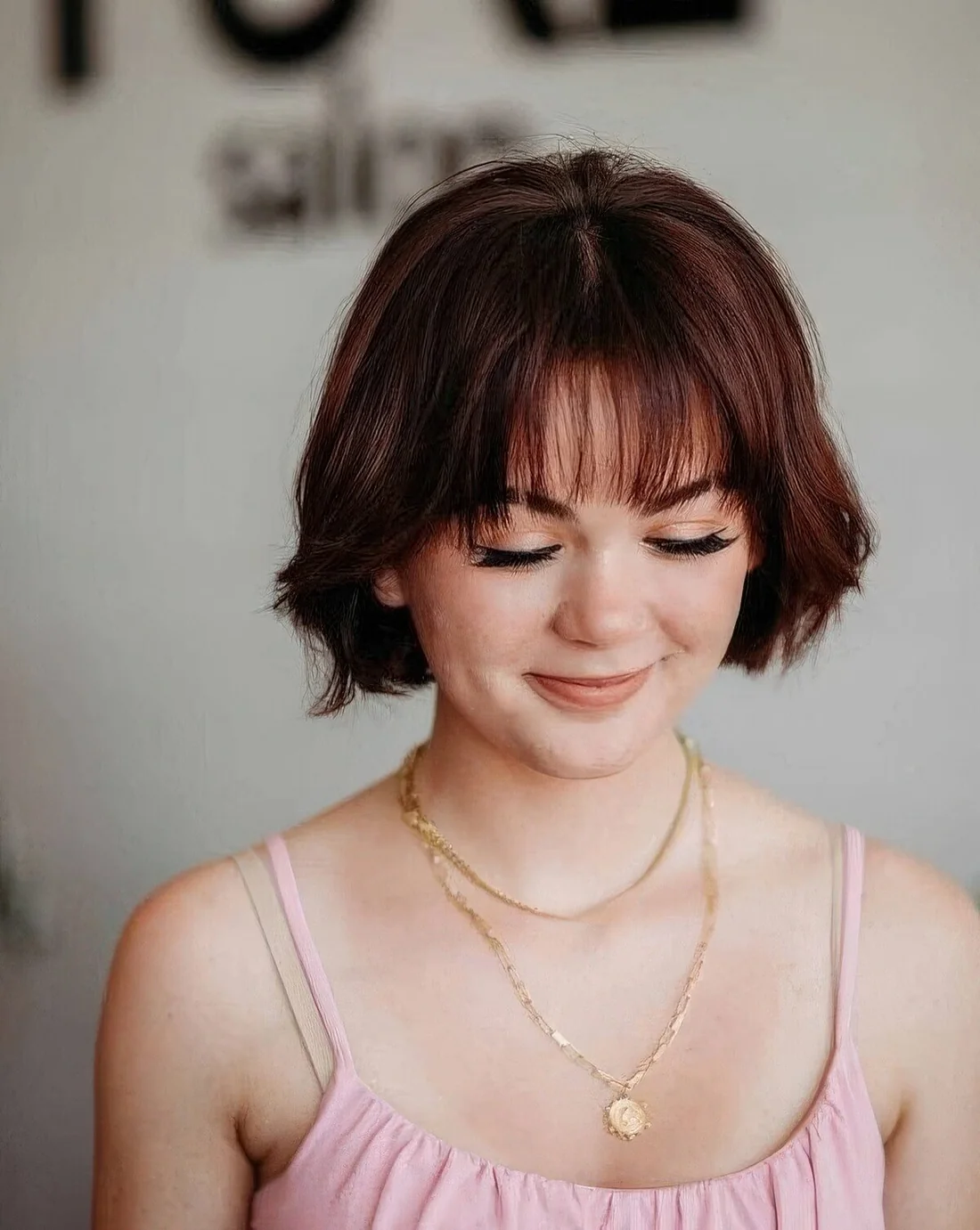 Auburn jaw-length bob with wispy bangs.