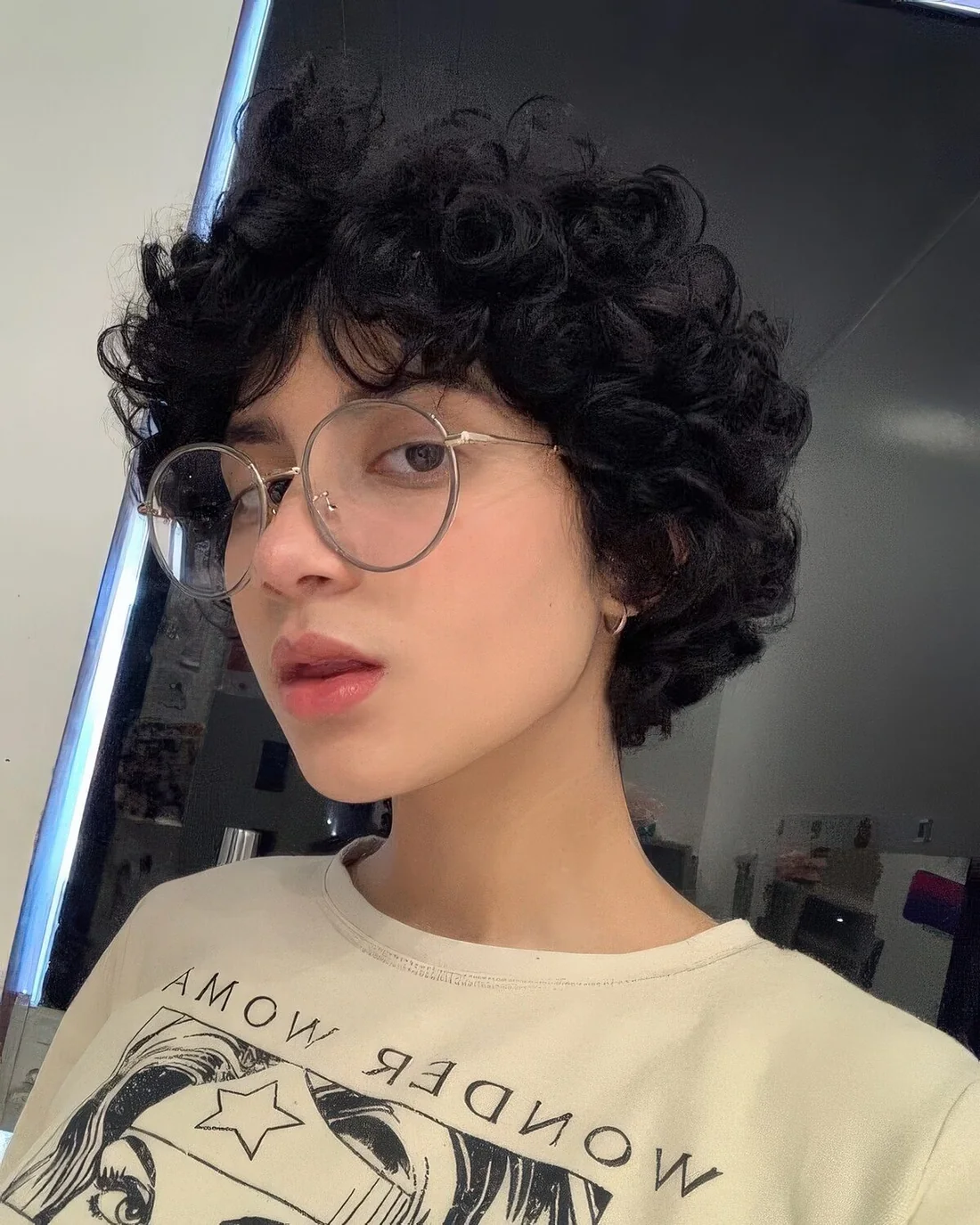 Black curly long pixie haircut with long bangs and some volume.