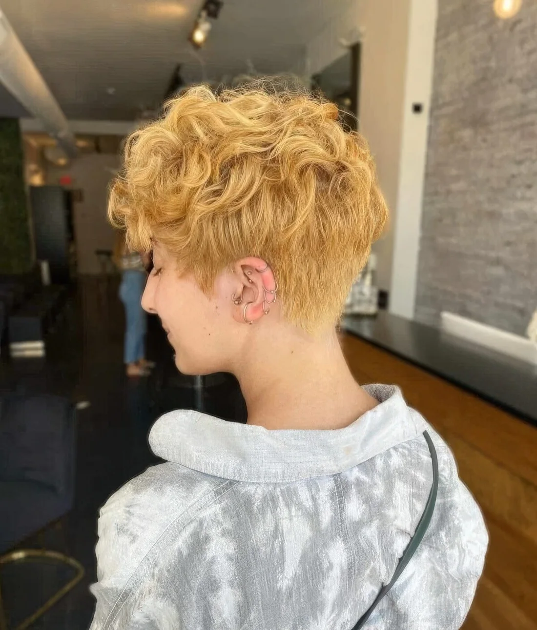 Tapered wavy pixie with bold edges and softness to bring the bulk of the curl towards the face.