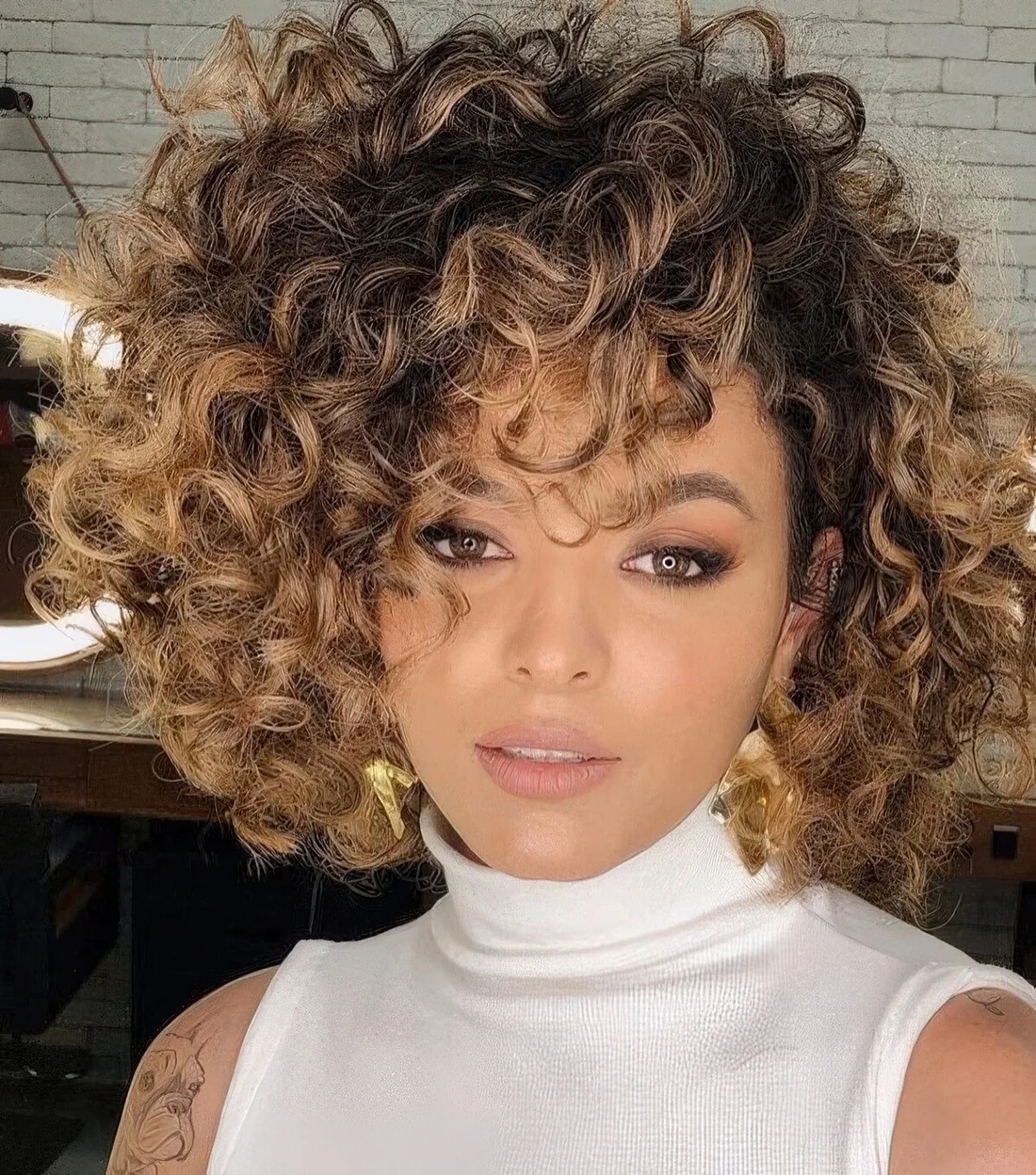 Chin-length curly bob with jaw dropping volume and caramel balayage.