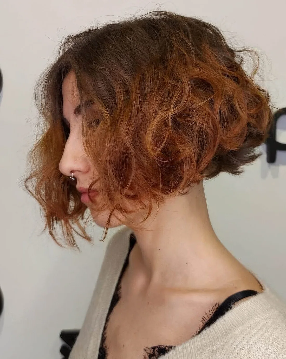 Short curly angled bob with a darker root and a ginger ombre.
