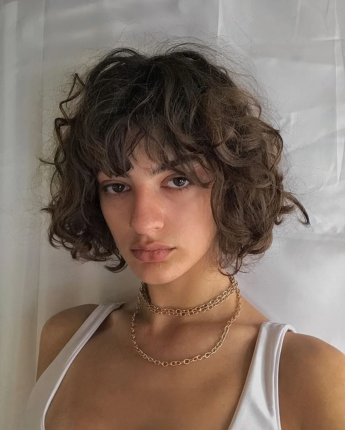 Jaw-length brunette curly bob with some volume.