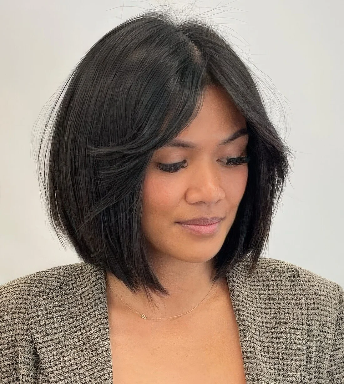 Black blunt bob with short curtain bangs and center part.