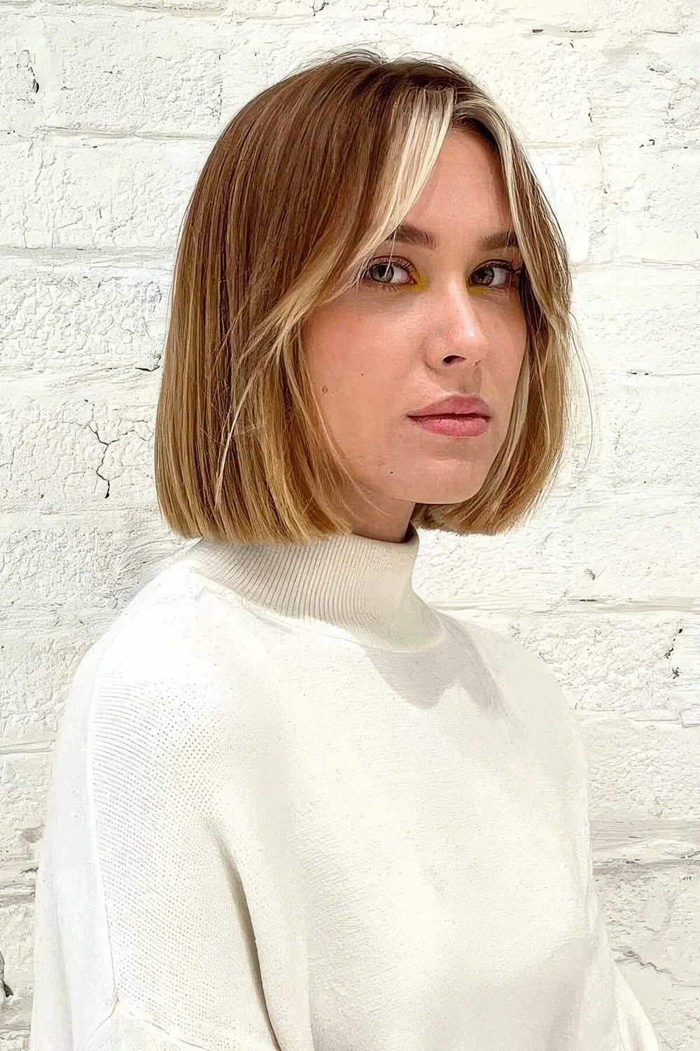 Brown to blonde ombre bob with short curtain bangs that are done icy blonde.