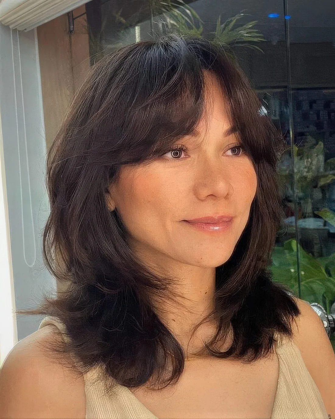 Dark medium-length hair with short curtain bangs, a texture and a bit of layers.