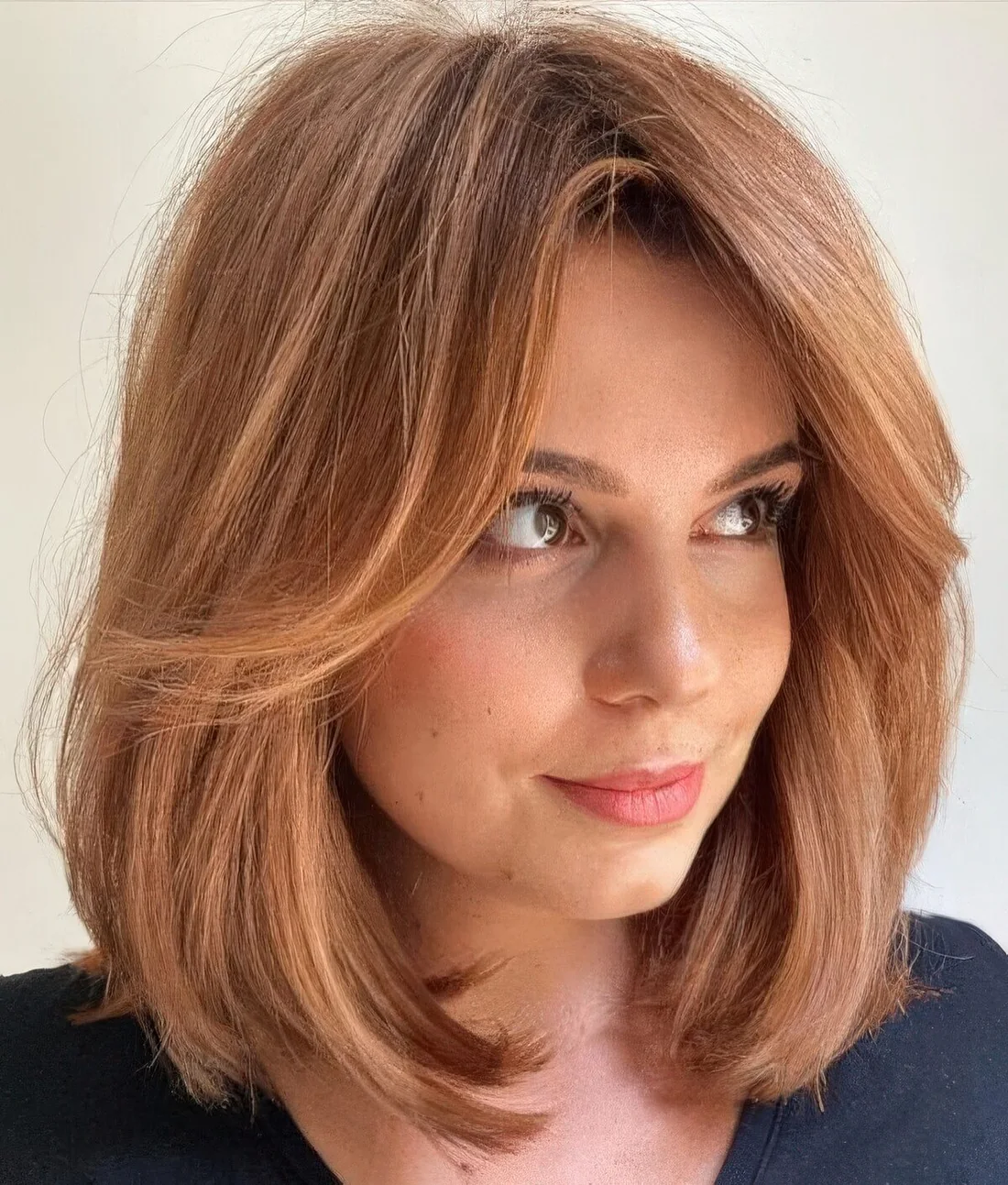 Ginger shoulder-length hair with short curtain bangs and a lot of volume.
