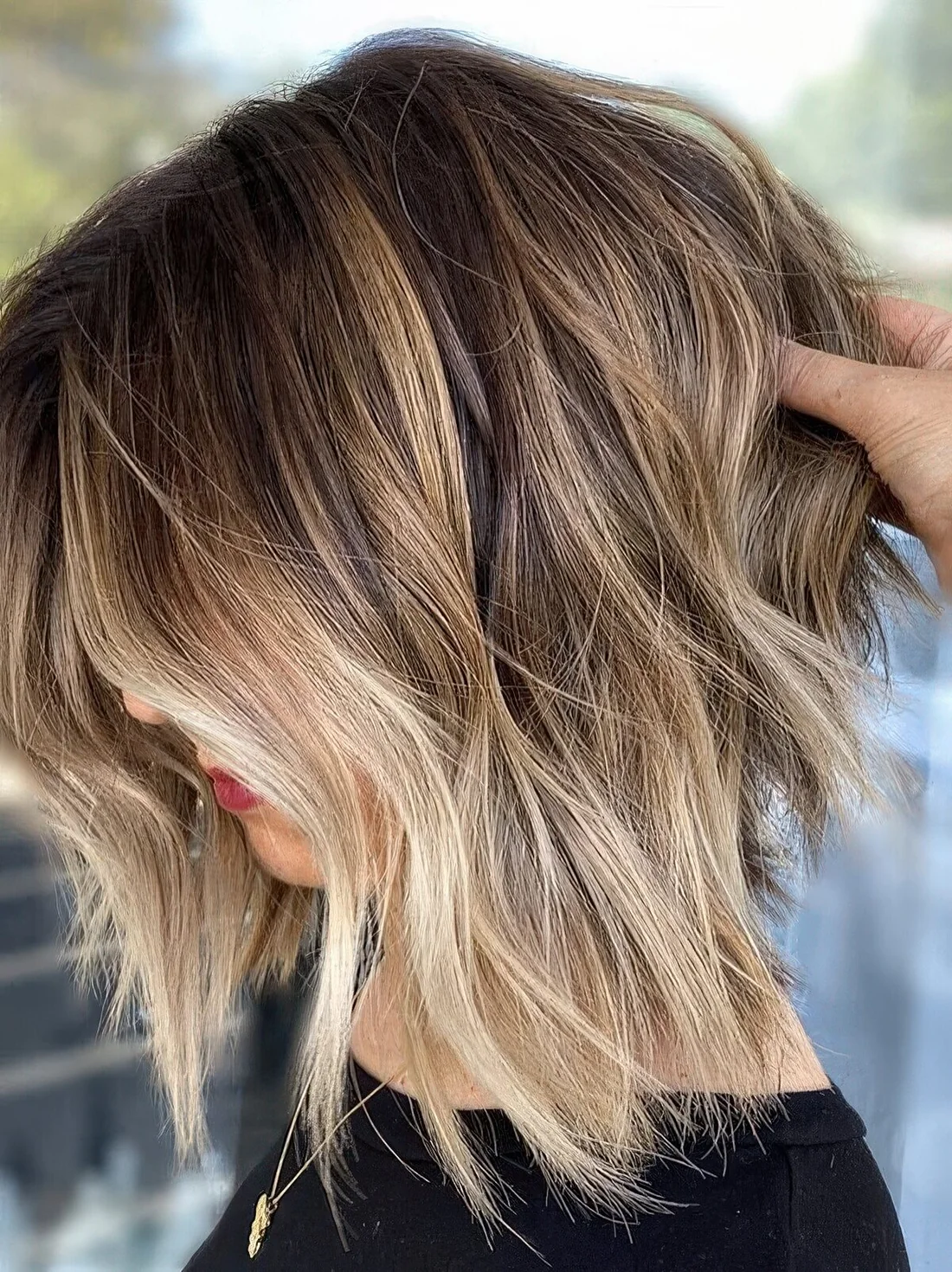 Brown bob wih blonde balayage, with messy waves and bangs.