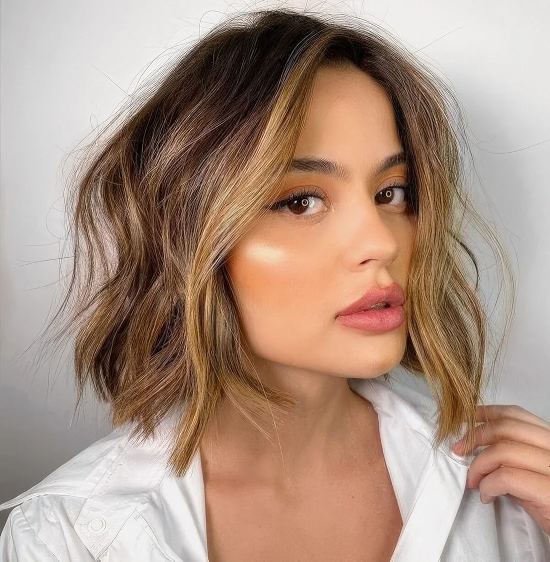 Brown bob with caramel balayage and a money piece, with volume and messy waves.