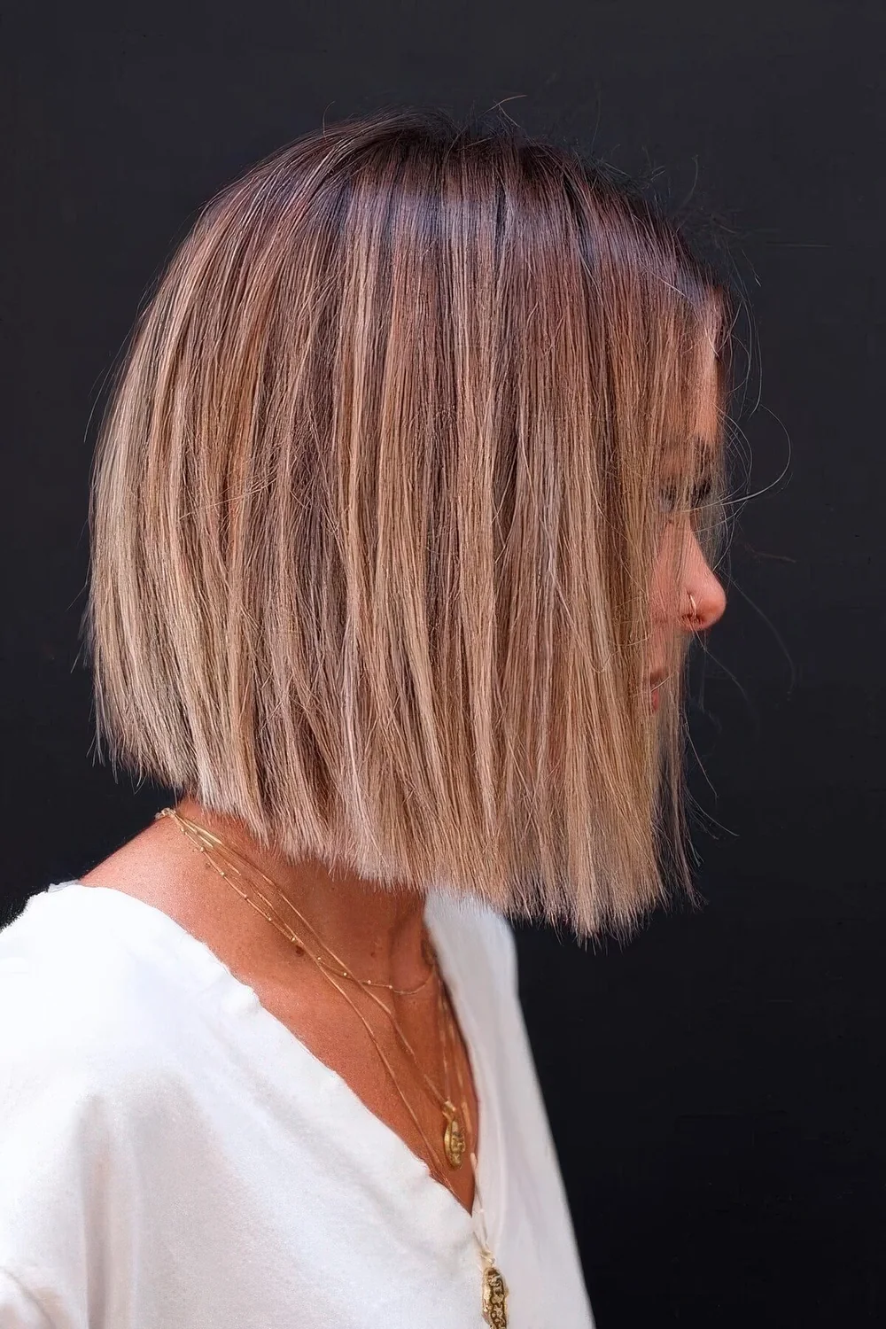 Cihc blunt bob with a brown root and blonde balayage.