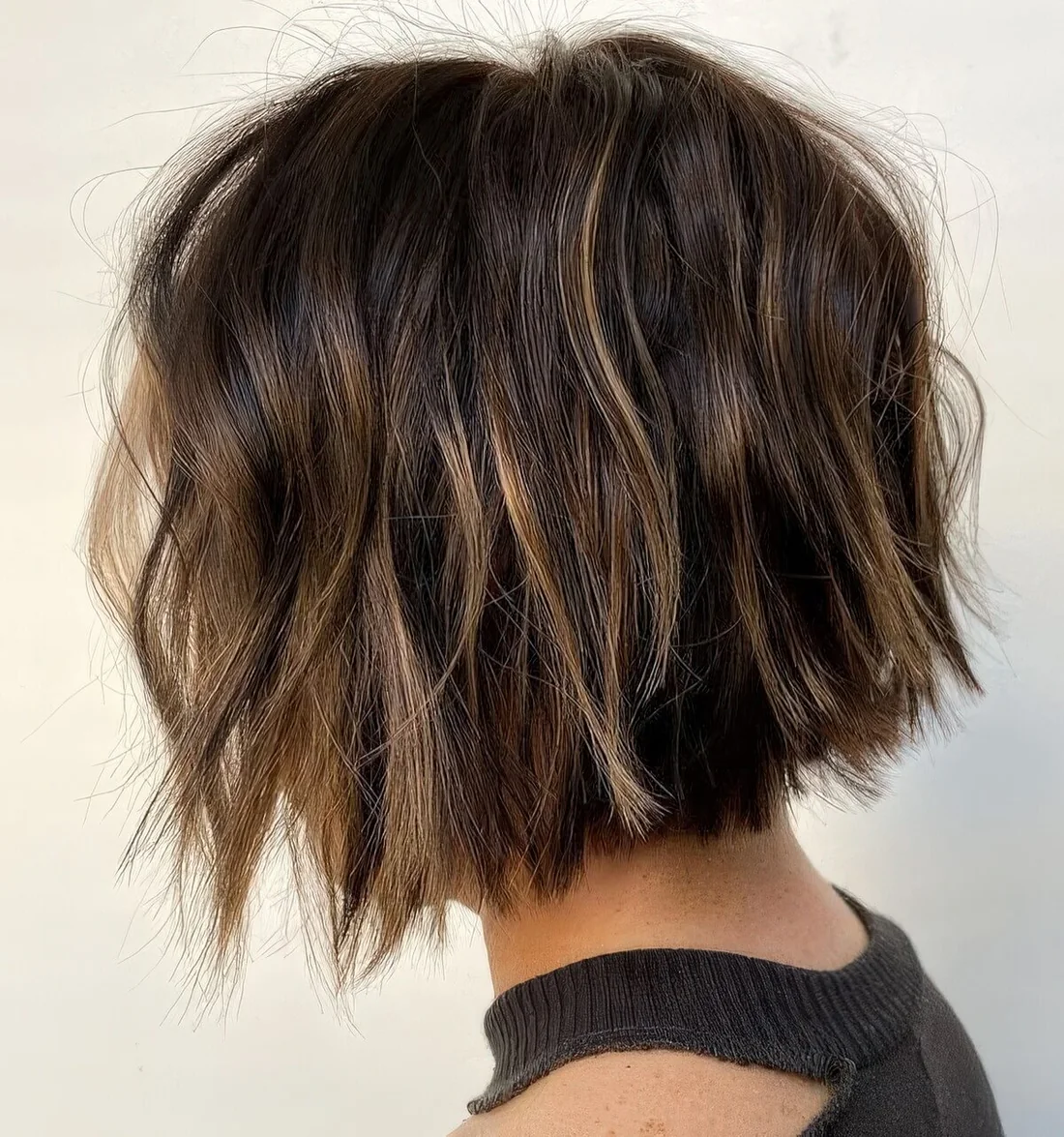 Dark brown short bob with blonde balayage and babylights, with messy waves.