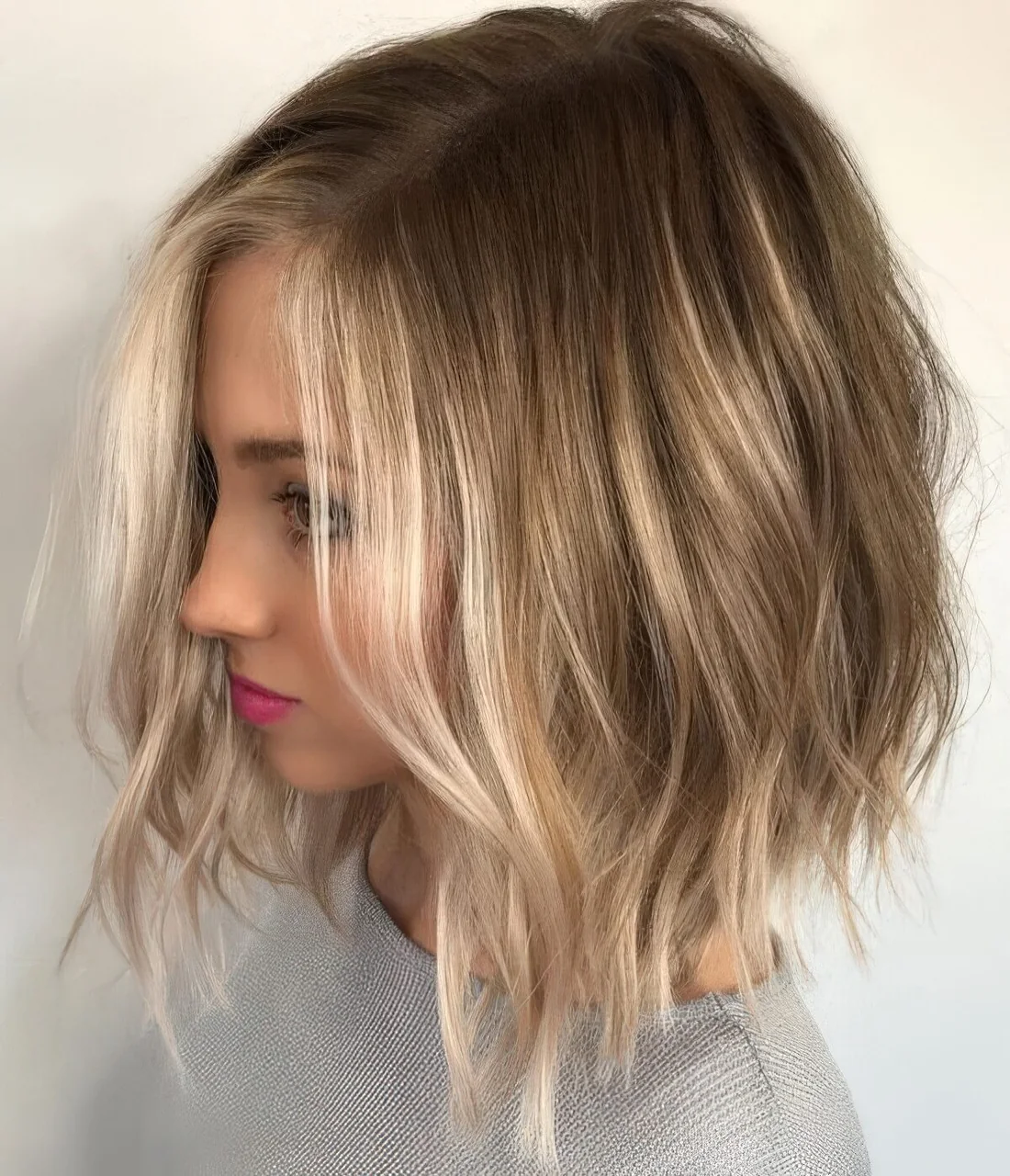 Light brown bob with blonde balayage and messy waves and texture.