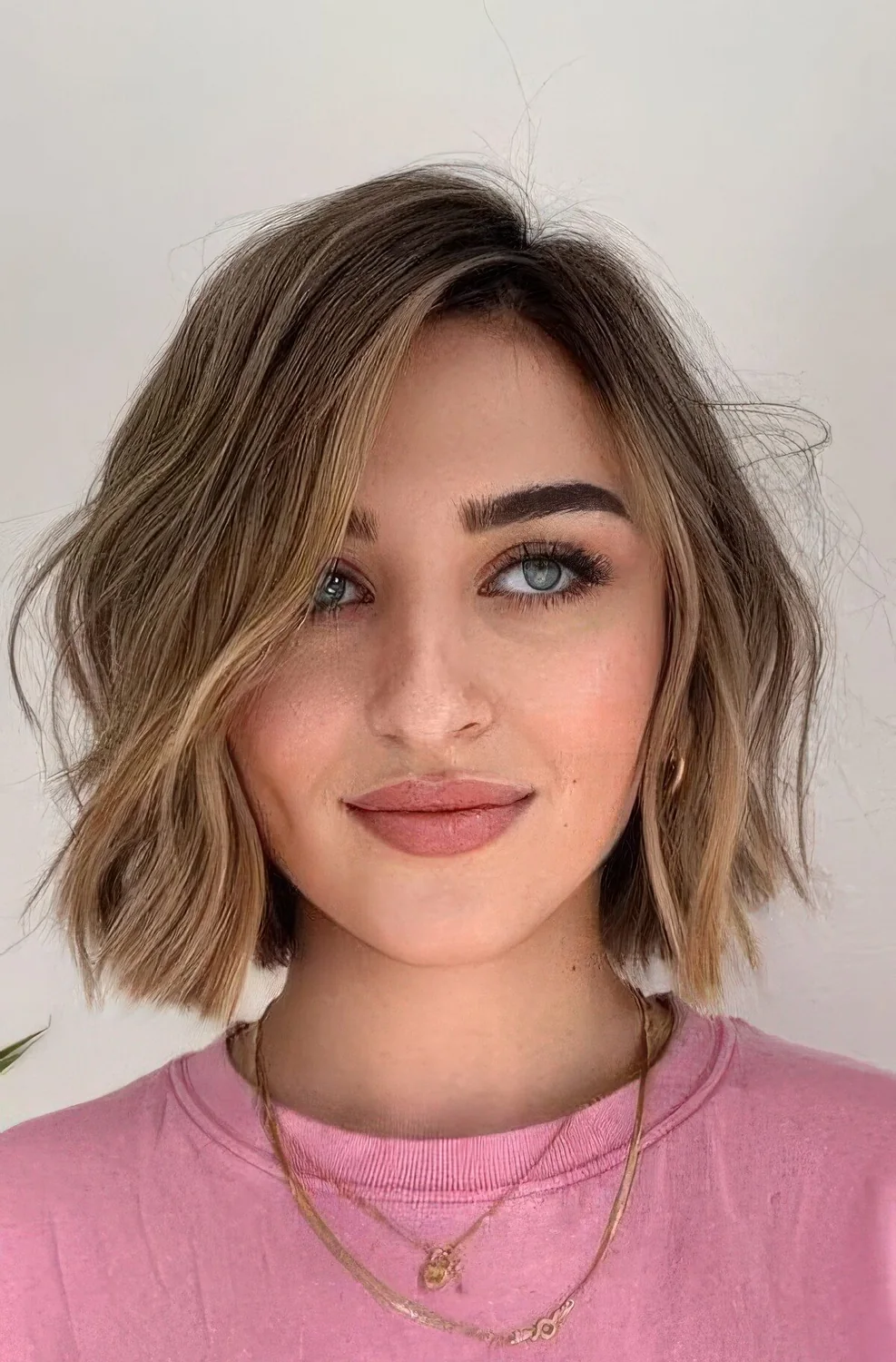 Light brown bob with much volume and texture, with ccaramel and bronde balayage and messy waves.
