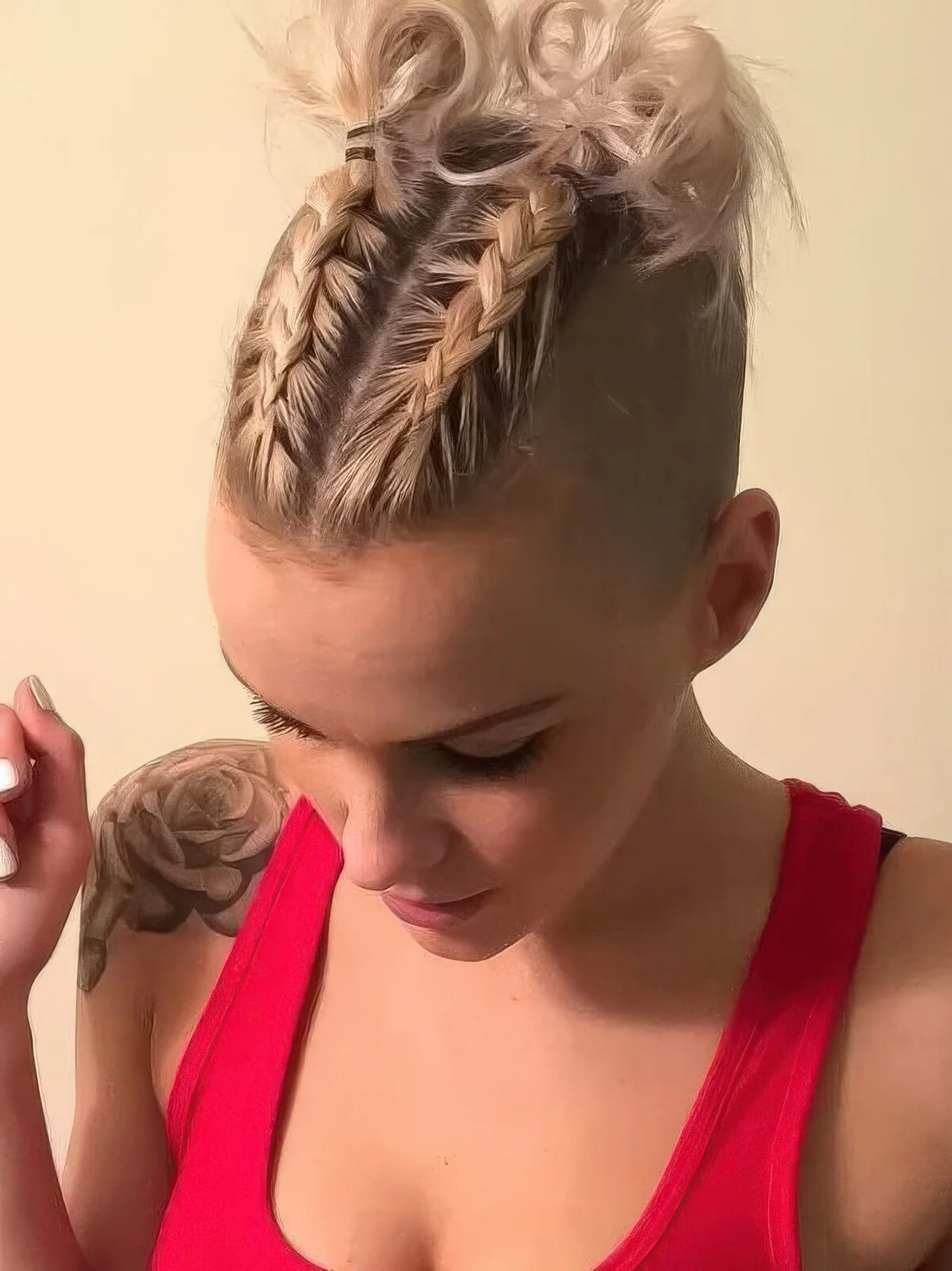 Short blonde hair styled with two braids on top and little curly buns at the ends.