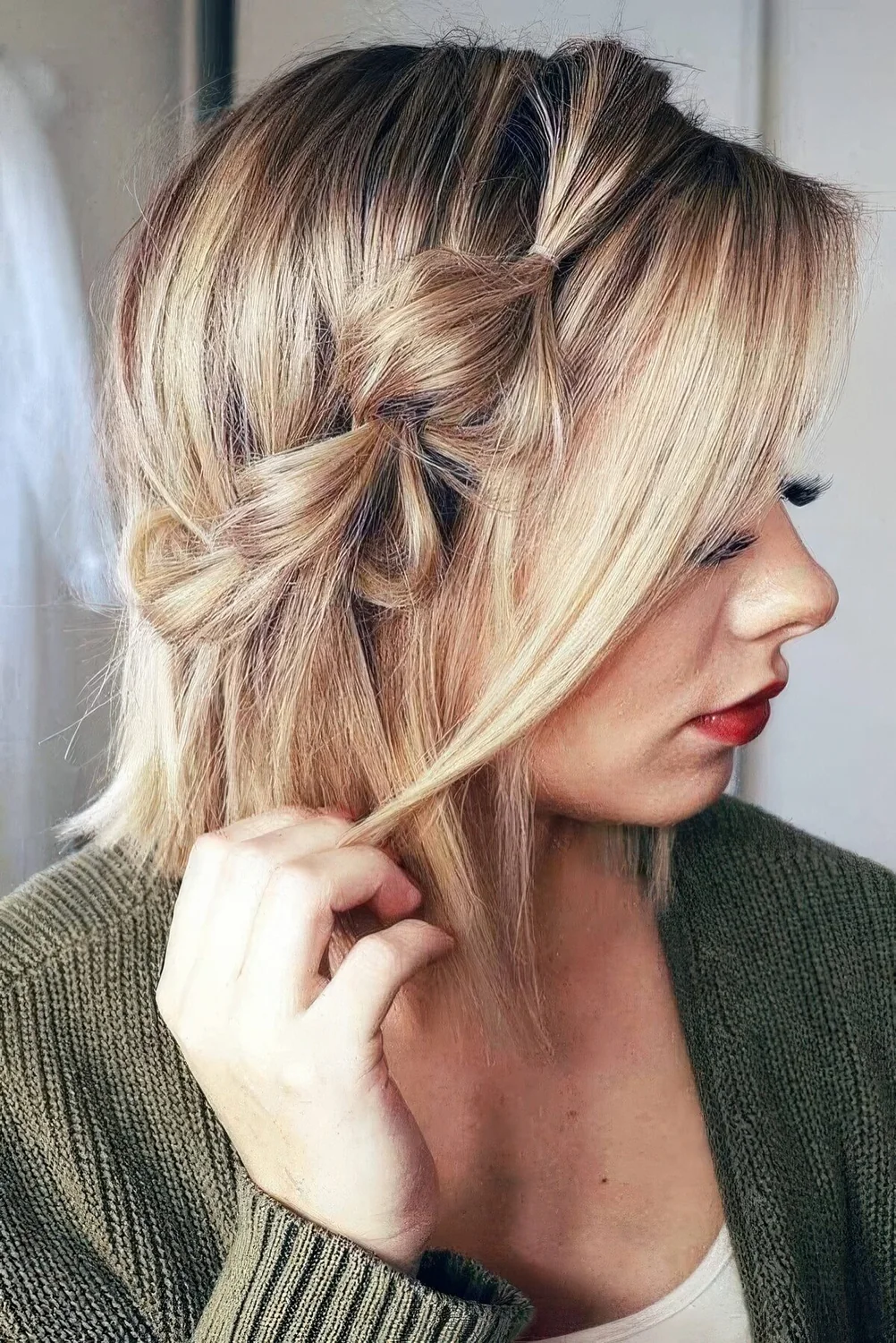 Blonde bob with a bubble side braid and some locks framing the face.